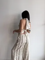 Pantalón de corte holgado y tiro alto, con diseño estampado de rayas verticales discontinuas en tonos beige y marrón. Presenta cintura elástica y caída fluida.