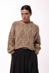 Sweater de tejido de punto grueso con diseño de rombos en relieve, cuello redondo y mangas largas amplias. Presenta una silueta relajada y holgada.