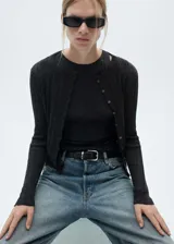 Cardigan de punto fino en color gris oscuro, con cuello redondo, manga larga y cierre frontal de botones pequeños. Presenta un diseño recto y tejido acanalado.