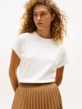 Remera blanca de algodón con cuello redondo y mangas cortas con dobladillo y botones dorados.