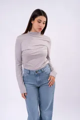 Polera de cuello alto bajo, manga larga, confeccionada en tejido liviano y elástico, con un ajuste al cuerpo.