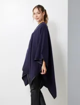 Ruana negra de tejido suave, con cierre frontal de botones metálicos y ribetes de cuero sintético en los bordes.