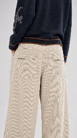 Pantalón de pana de algodón con tiro medio y corte de pierna ancha. Presenta dos bolsillos delanteros, dos bolsillos traseros con pespuntes y cierre frontal con botón y cremallera.