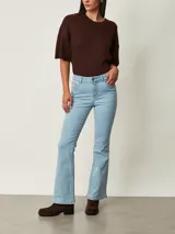 Pantalón jean de tiro medio, corte flare en color celeste claro, con bolsillos delanteros y traseros y cierre de botón y cremallera.