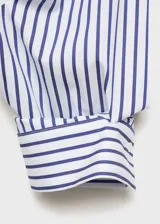Camisa de corte recto y diseño crop, con estampado de rayas verticales en azul y blanco. Presenta cuello camisero, cierre frontal con botones y un bolsillo en el pecho.