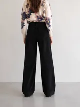 Pantalon de pana color negro, de tiro alto y corte wide leg. Presenta diseño clásico de cinco bolsillos, cierre frontal con botón y una caída amplia y recta.