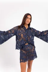 Camisa de molde clásico confeccionada en encaje bordado tipo guipur, color azul, con mangas largas amplias y aplicación de tachas doradas.