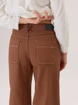 Pantalon de corte ancho y holgado, confeccionado en mezcla de algodón, viscosa y lino. Presenta costuras decorativas, pinzas debajo de la rodilla, bordado de monograma en el bolsillo delantero y pespuntes a contratono.