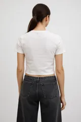 Remera de algodón color marrón, de corte crop y ajuste al cuerpo, con cuello redondo y aplique central en forma de corazón con estampado a cuadros.