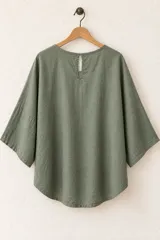 Remera de algodón color verde militar, de corte holgado, con mangas cortas amplias, cuello redondo y un bolsillo aplicado en el pecho.