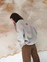 Sweater de lana gris con diseño de líneas y formas geométricas en color rosa.