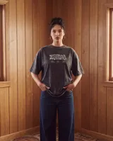Remera de algodón con efecto lavado stone wash, de corte oversize y manga corta. Presenta un diseño gráfico estampado en la espalda con tipografía artística y texto alusivo a la cultura de barrio.