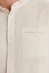 Camisa de cuello mao y manga larga, confeccionada en una mezcla de lino y algodón. Presenta un diseño de corte recto con botones en tono natural y un bolsillo pequeño en el pecho.