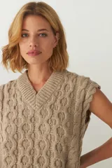 Chaleco de punto color crema con diseño trenzado y cuello en V.