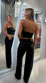 Pantalón de jean negro de calce wide leg y tiro medio, con detalle de estrellas brillantes en los bolsillos traseros.