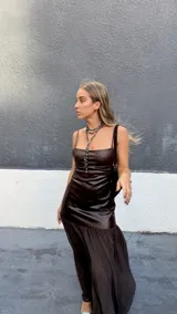 Vestido largo de diseño combinado, con cuerpo superior ajustado de efecto cuero en color chocolate y falda inferior fluida de gasa semitransparente. Presenta escote recto con breteles finos.