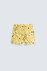 Bañador de hombre de tejido técnico ripstop, color mostaza con estampado floral abstracto en blanco y negro. Presenta cintura elástica ajustable con cordón, bolsillos laterales y bolsillo trasero de plastrón.