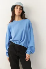 Buzo celeste cropped de manga larga con puños y cordones ajustables en la cintura.