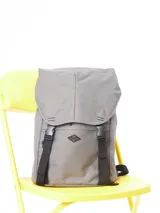 Mochila gris de lona 100% poliéster con cierre superior con solapa y hebillas plásticas. Tiene correas de ajuste frontales y logo de la marca estampado en el frente.