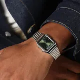 Reloj Casio estilo vintage con diseño ana-digi, caja de acero inoxidable de 30mm y esfera color verde oliva. Cuenta con brazalete de acero plateado, funciones de hora dual, cronómetro, alarma y calendario automático.