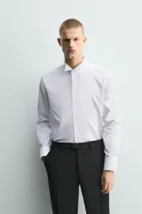 Camisa slim fit de algodón en color blanco, con cuello smoking y manga larga con puño doble abotonado.