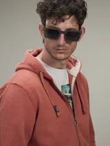 Buzo tipo hoodie con cierre frontal completo, capucha con cordones ajustables y bolsillos laterales. Confeccionado en tejido de algodón con textura jaspeada.