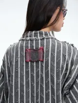 Camisa larga de diseño patchwork con cierre frontal de botones, confeccionada mediante la combinación de paneles con estampados de rayas, cuadros escoceses y motivos florales, con terminaciones deshilachadas.