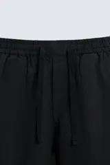 Pantalón de corte relajado color beige confeccionado en tejido de mezcla de algodón y lino. Posee cintura elástica ajustable con cordón, bolsillos frontales y bolsillos traseros de vivo.