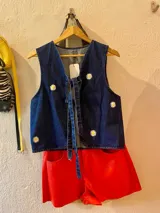 Chaleco de denim azul con bordado de margaritas blancas y logo de la marca en la parte superior.