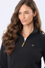 Buzo de polar color crema con cuello alto y cierre frontal parcial. Presenta detalles en cuero en el tirador del cierre y un pequeño bordado en el pecho y en la manga.