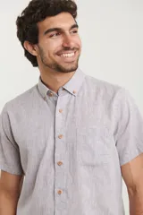Camisa azul de manga corta, con cuello abotonado y bolsillo en el pecho.