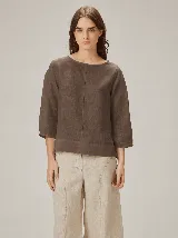Blusa de algodón color marrón, con escote redondo, mangas tres cuartos con volumen sutil y costuras verticales decorativas en el frente.