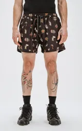 Short de baño negro con estampado de estilo tatuaje old school, que incluye diseños de rosas, sirenas, tiburones, anclas y diamantes. Cuenta con cintura elástica, cordón ajustable y cuatro bolsillos.