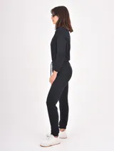 Monoprenda de estilo deportivo color negro, con cierre frontal parcial, mangas largas y cintura elástica con cordón ajustable. Presenta un diseño de pantalón tipo jogger con puños en los tobillos.