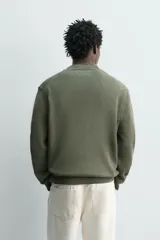 Sweater de punto negro de corte regular fit, confeccionado en algodón con cuello redondo, manga larga y acabados en rib.