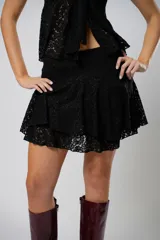 Pollera corta de encaje negro con diseño de volados escalonados y terminación con borde festoneado.