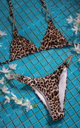 Conjunto de bikini fucsia con corpiño triangular y bombacha clásica con argollas plateadas con strass en los laterales.