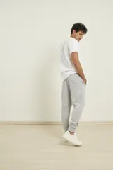 Pantalón de jogging color verde militar, corte slim, con puños elastizados en los tobillos y cordón ajustable en la cintura. Presenta un bolsillo lateral con cierre.