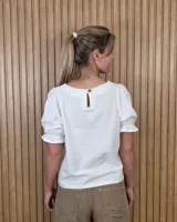 Blusa blanca de corte recto con escote a la base y mangas cortas abullonadas con terminación fruncida.
