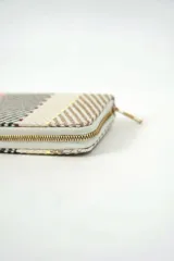 Billetera rectangular de diseño tejido con rayas multicolor en tonos rojo, azul, blanco y negro, con cierre perimetral dorado.
