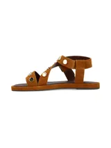 Sandalia plana de cuero gamuza en color camel, con tiras decoradas con tachas metálicas doradas y hebilla metálica de ajuste lateral.