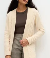 Cardigan alargado Marfinno de punto texturizado color marfil, con diseño abierto, mangas largas y puños canelados.
