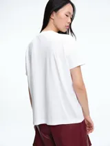 Remera blanca de corte oversize con la palabra 'Cute' escrita en el frente mediante apliques de strass brillantes.