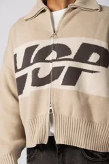 Campera tejida de punto con cierre frontal completo y cuello polo. Presenta un diseño con franja horizontal en color azul y letras en blanco sobre fondo negro, con puños y ruedo acanalados.