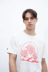 Remera negra de algodón con cuello redondo y manga corta. Estampado central en tono celeste/azul claro que simula corales o algas marinas dentro de un círculo, con el texto "1956" arriba y "Good Times With Your People" abajo.