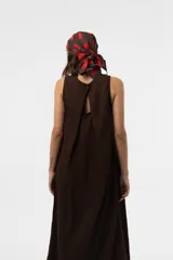 Vestido midi sin mangas de color marrón, confeccionado con textura arrugada, escote redondo, silueta relajada y caída liviana, con un lazo fino ajustable en la cintura.
