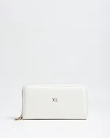 Billetera grande de cuero sintético texturizado en color blanco, con cierre perimetral dorado y logo metálico "XL" en el frente.