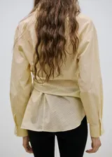 Camisa cruzada de manga larga con lazos para atar en la cintura y cuello camisero, con sutiles rayas verticales.