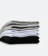 Pack de tres pares de medias deportivas Puma de caña corta, confeccionadas en tejido de algodón con textura. Incluye un par negro, uno blanco y uno gris, cada uno con el logo de la marca en el talón y el nombre en la parte superior.