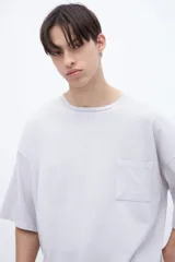 Remera color gris claro, de algodón lavado con textura extra suave, calce boxy y bolsillo en el pecho.